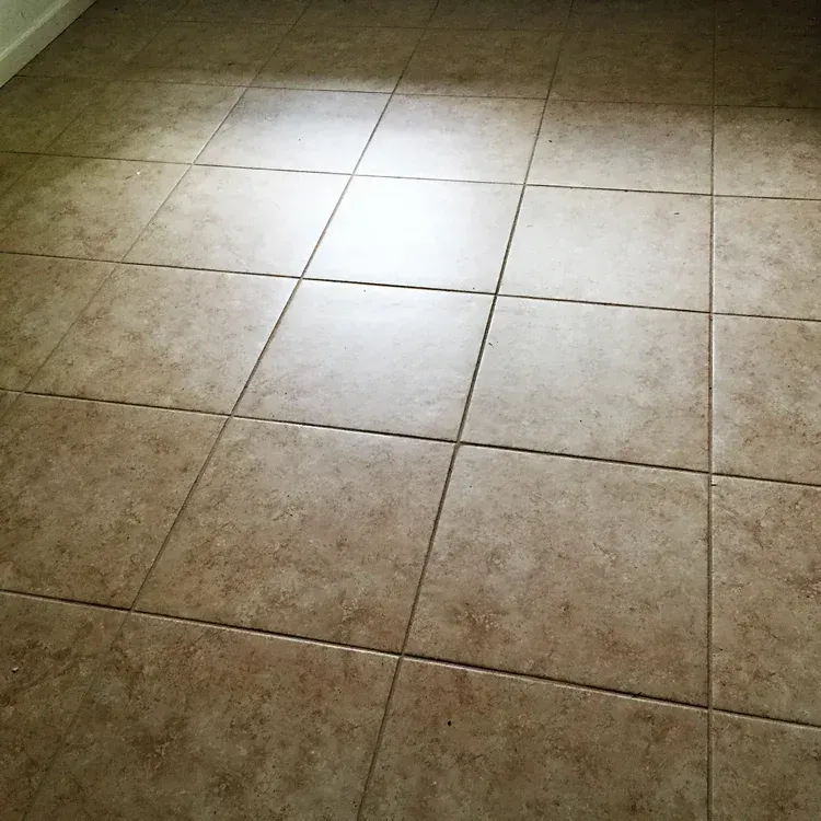 Beige tiled floor with light reflection.