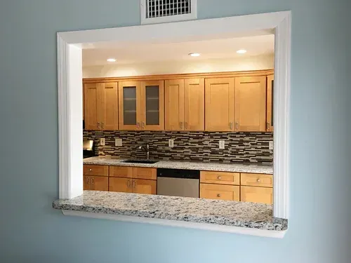 Kitchen pass-through with granite countertop.