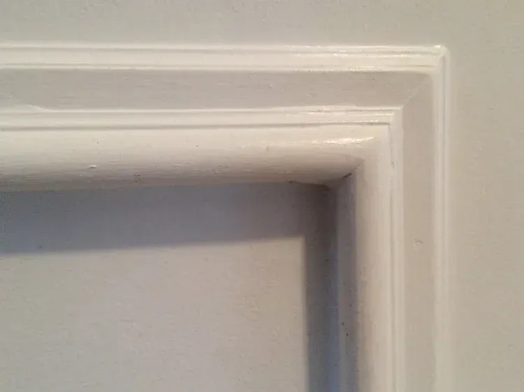 White painted door trim detail, showing layered rectangular design with slight rounded edges.