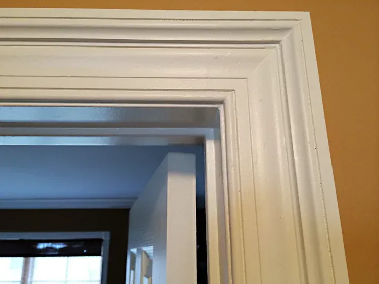 White painted door frame with ornate molding against a light brown wall.