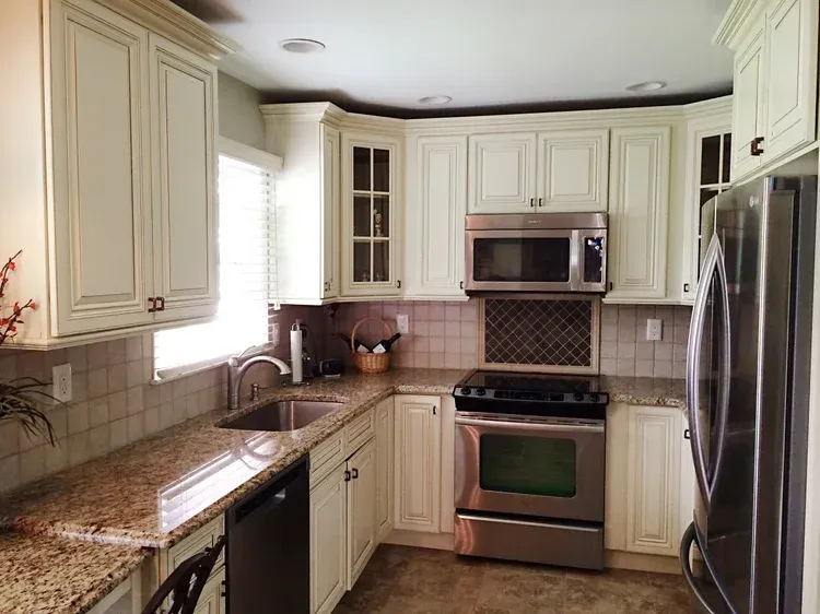 Cream-colored kitchen cabinets with granite countertops, stainless steel appliances, and a tile backsplash.