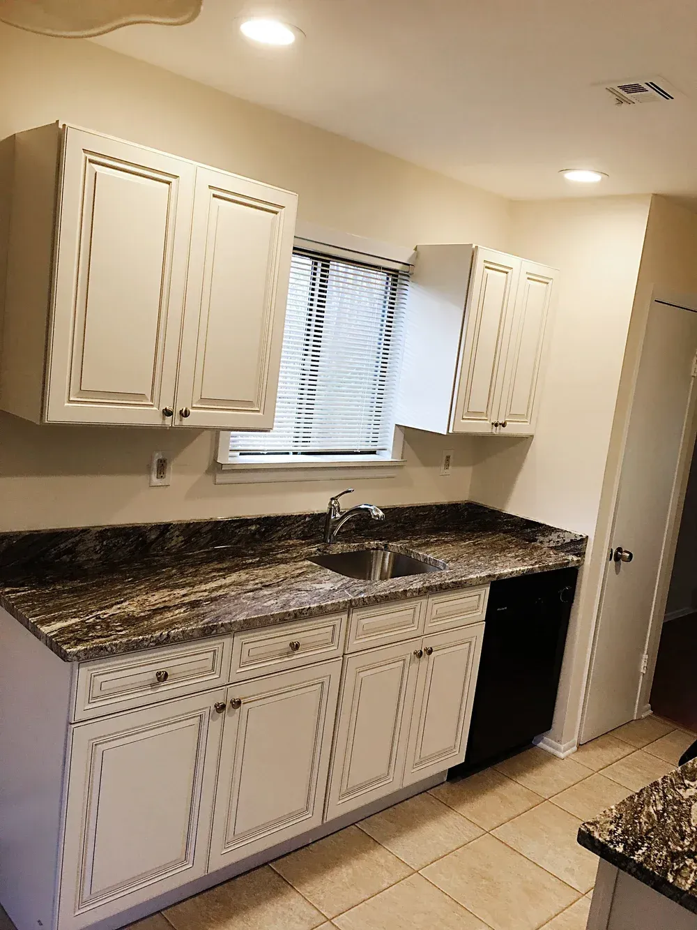 Kitchen with white cabinets, dark countertops, and a black dishwasher.