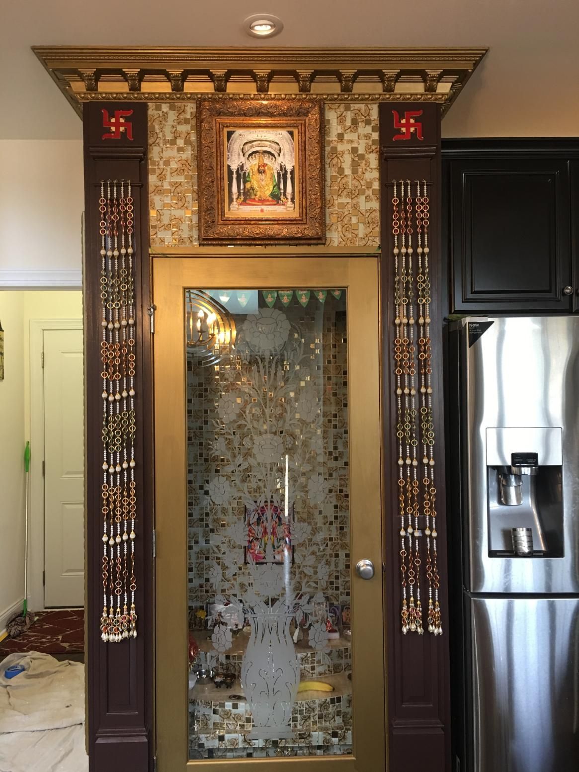 Ornate doorway with gold accents, mosaic tile, artwork, and a frosted glass door.