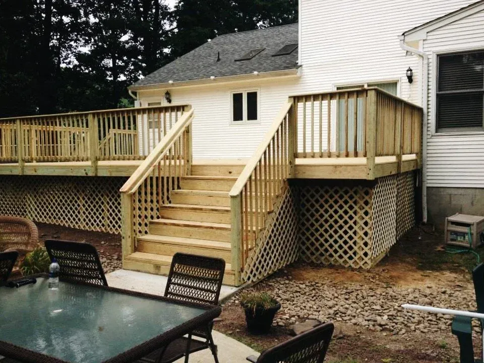Wooden deck with stairs, lattice skirting, and a dining table.