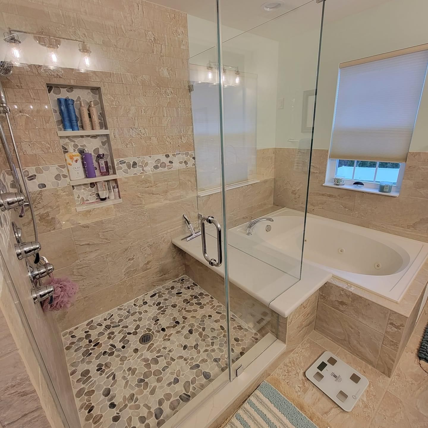 Bathroom with stone tile shower, built-in tub, and glass door.