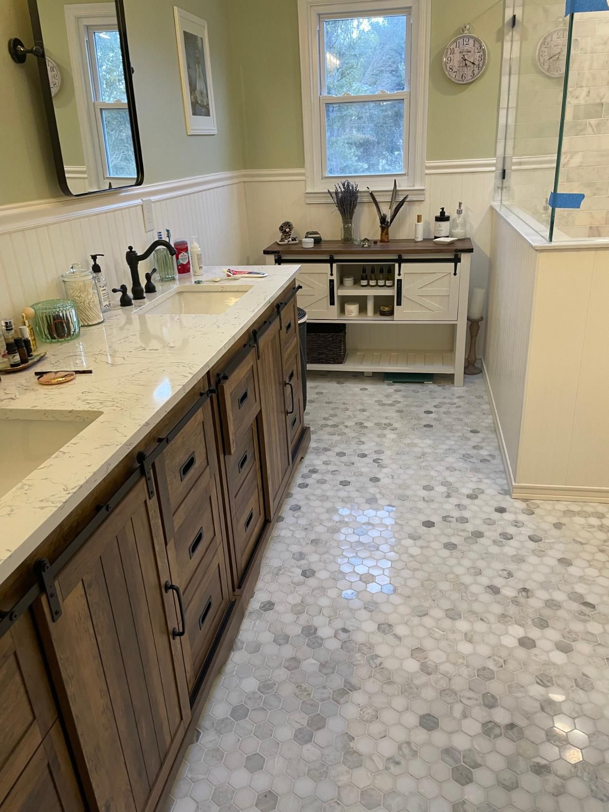 Bathroom with wood vanity and white countertop, hexagon tile floor, and a window.