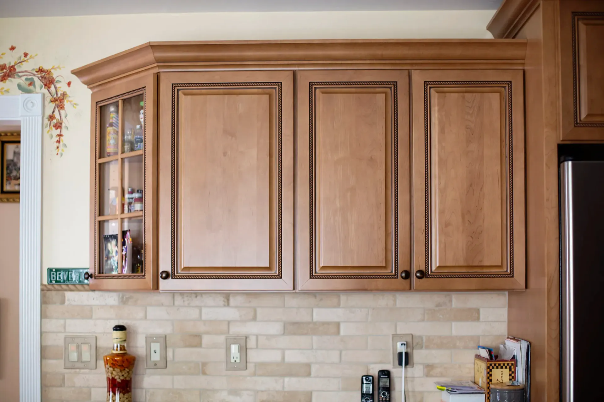 Wooden kitchen cabinets with light-colored doors and decorative trim above a tiled backsplash.
