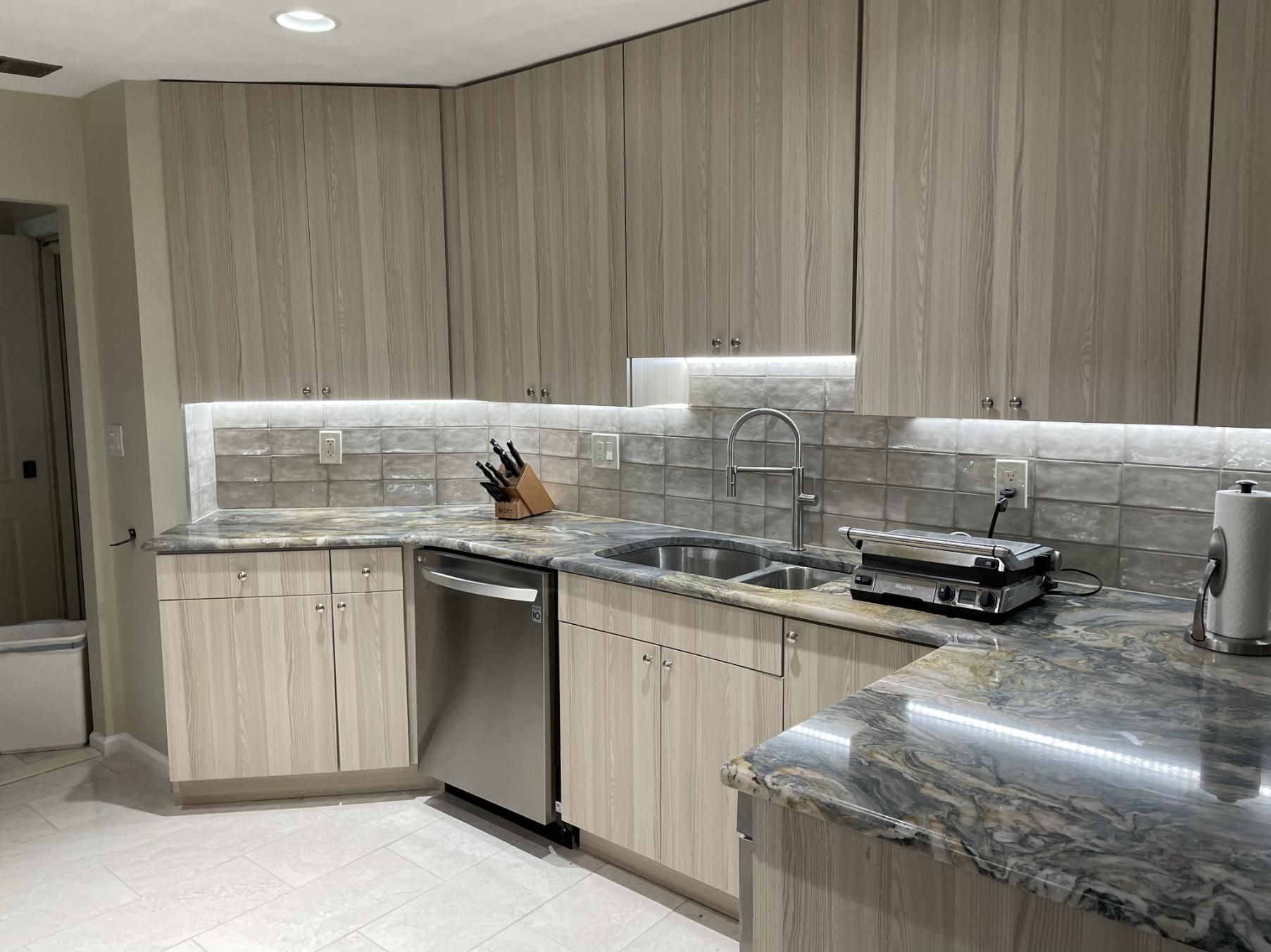 Modern kitchen with light wood cabinets, stainless steel appliances, and granite countertops.