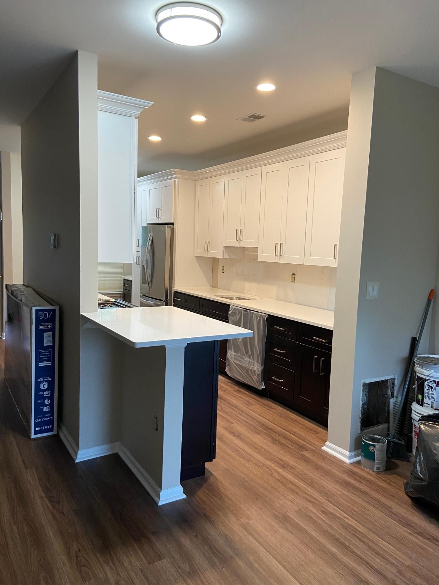 Newly renovated kitchen with white upper cabinets, dark lower cabinets, and a breakfast bar.