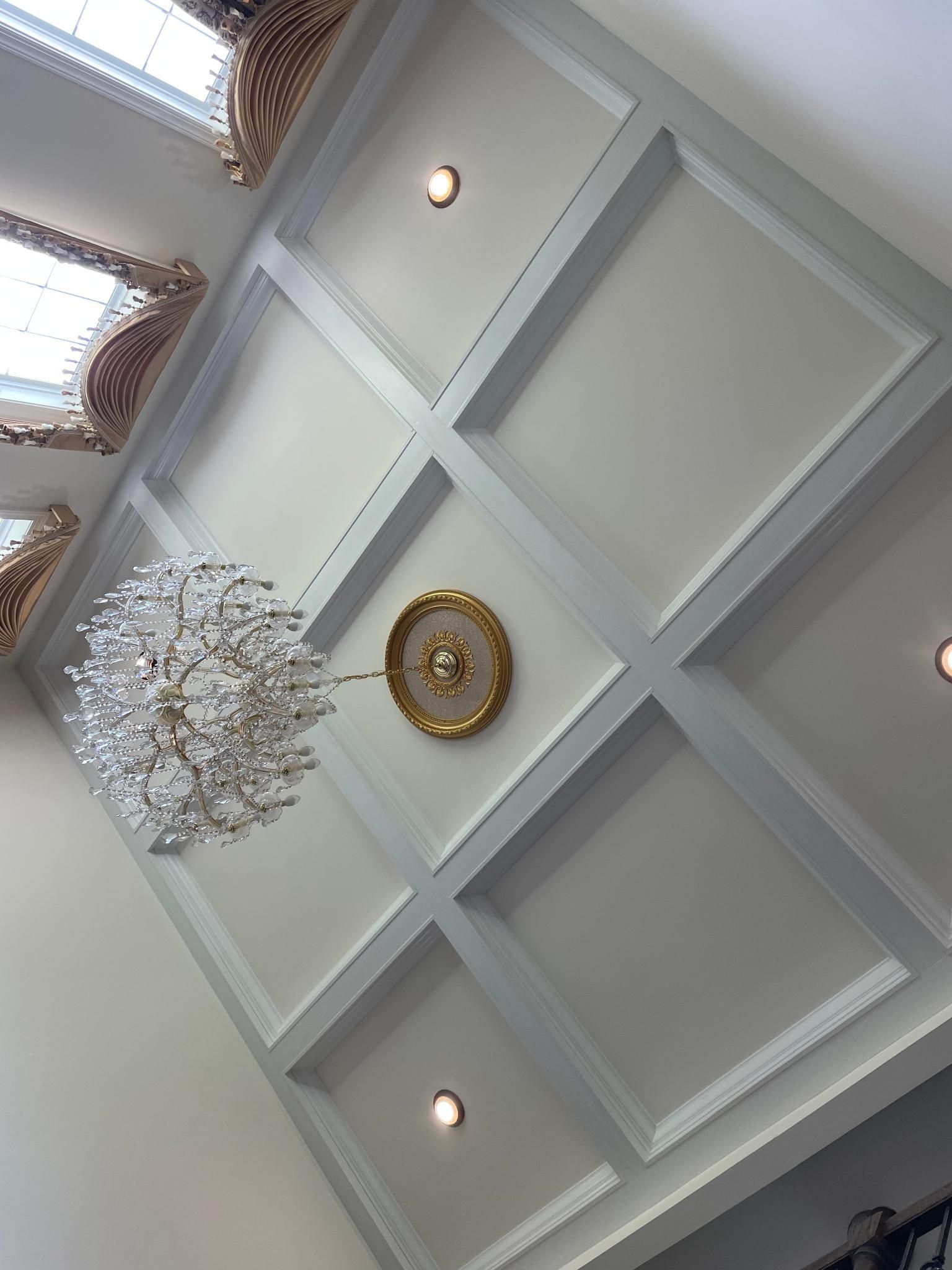 White coffered ceiling with gold and silver chandelier, and small circular lights.