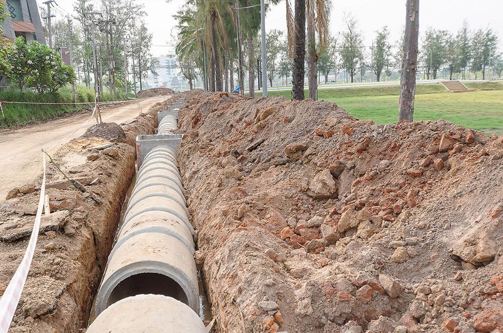 Un mucchio di tubi giace nella terra in una trincea.