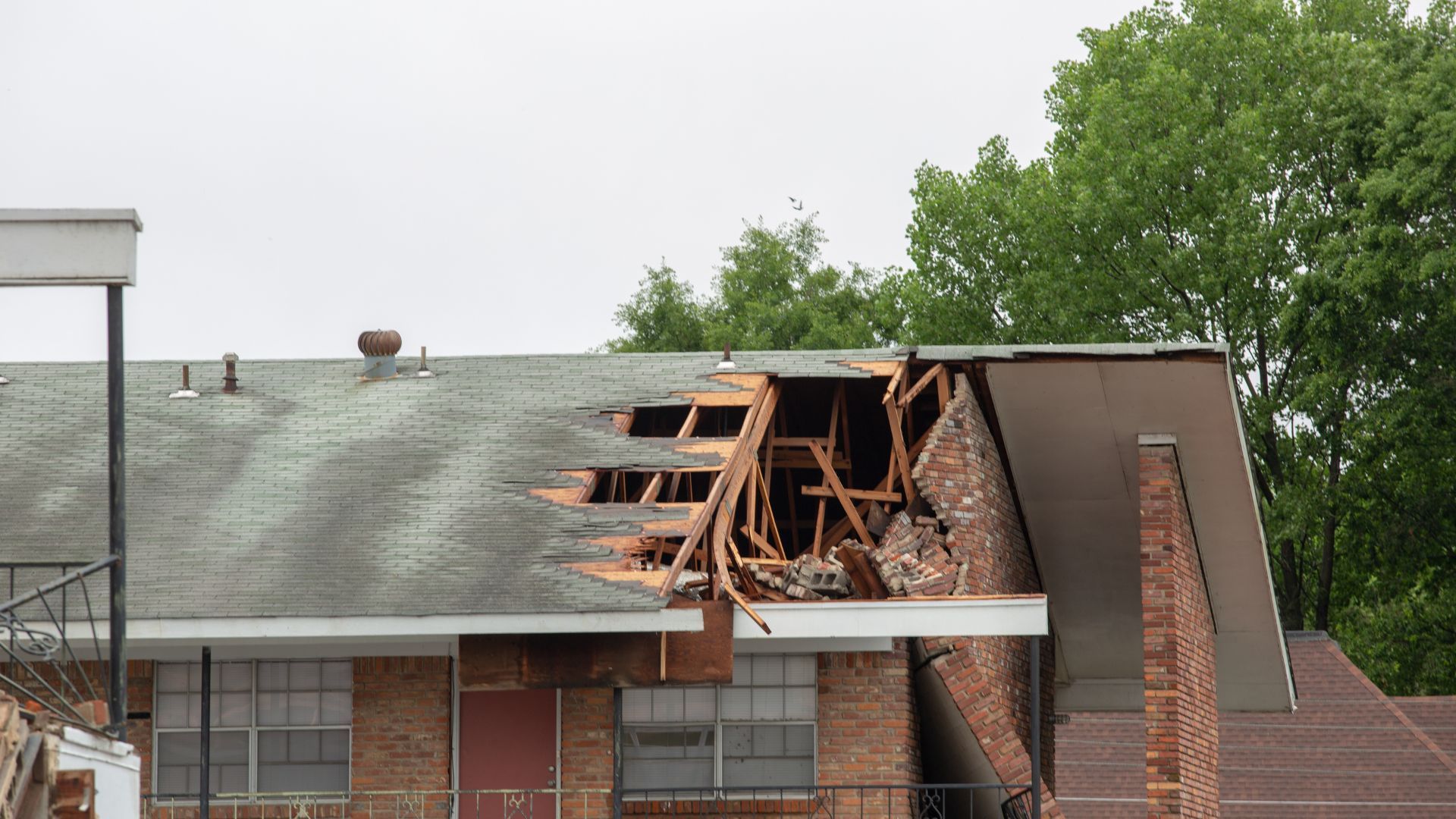 A brick building with a roof that has been damaged by a storm.
