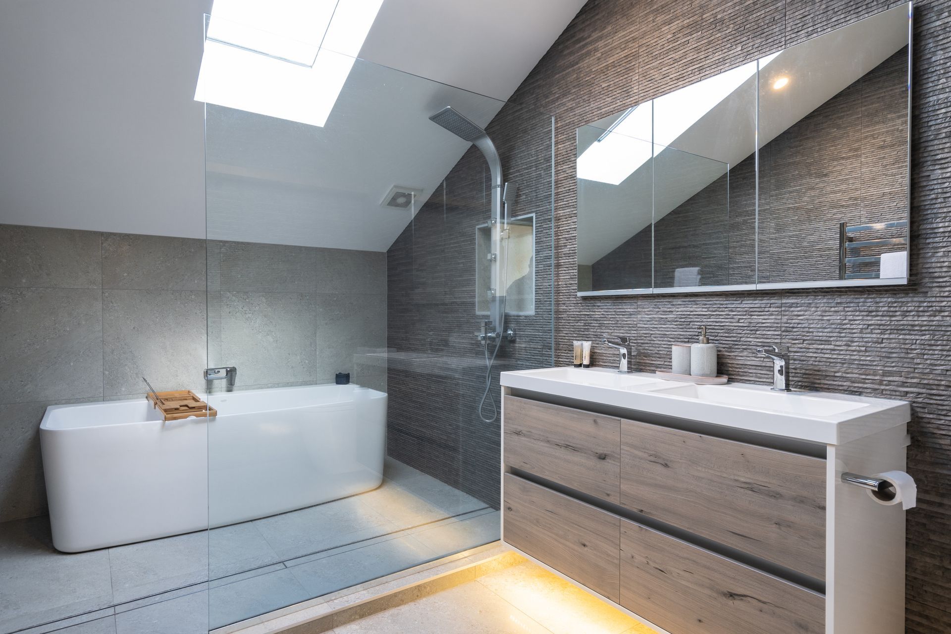A bathroom with a bathtub , sink , mirror and skylight.