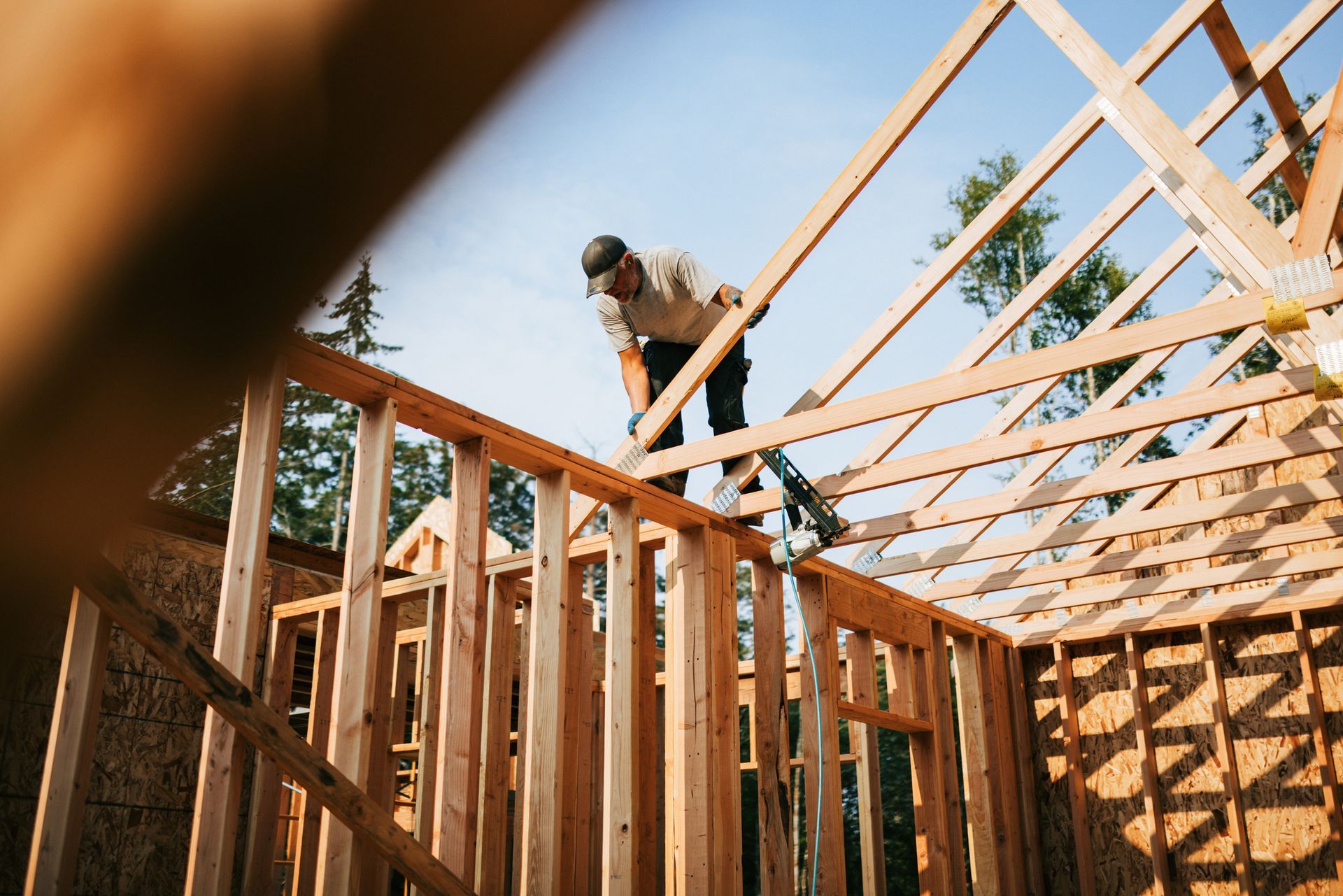 Building construction crew framing a new home with wood beams at a residential site.