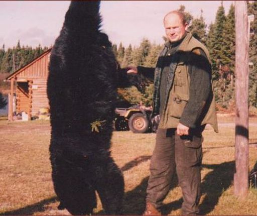 A man standing next to a large black bear