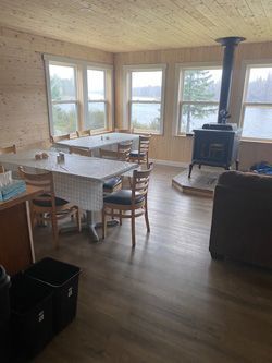 A large room with tables and chairs and a wood stove.