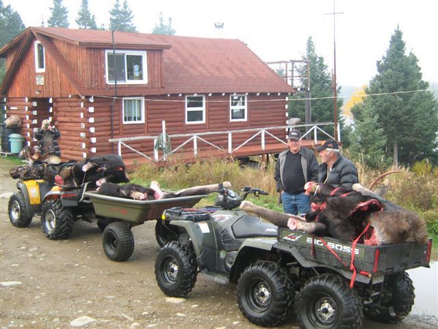 Three atvs are parked in front of a log cabin