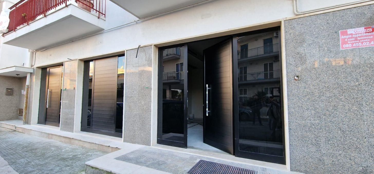 Vetrine di appartamenti con cancelli in metallo nero e facciata in granito grigio, viste da un marciapiede.