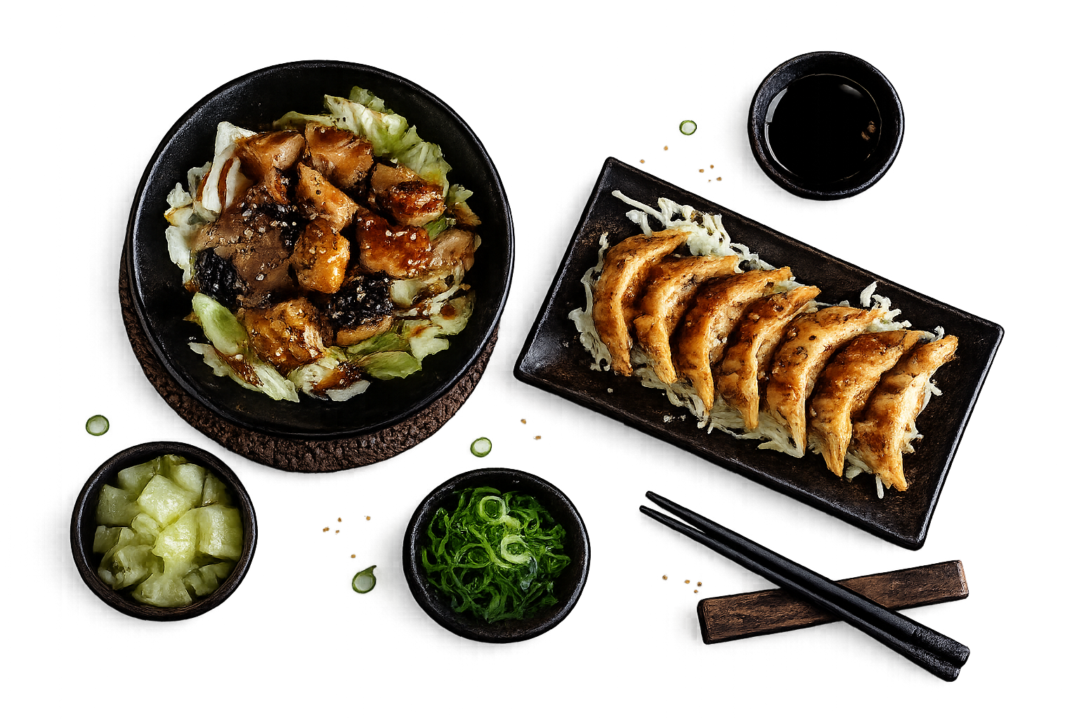 A bowl of teriyaki chicken over cabbage, a plate of six gyoza, soy sauce, chopped scallions, and pickled ginger.