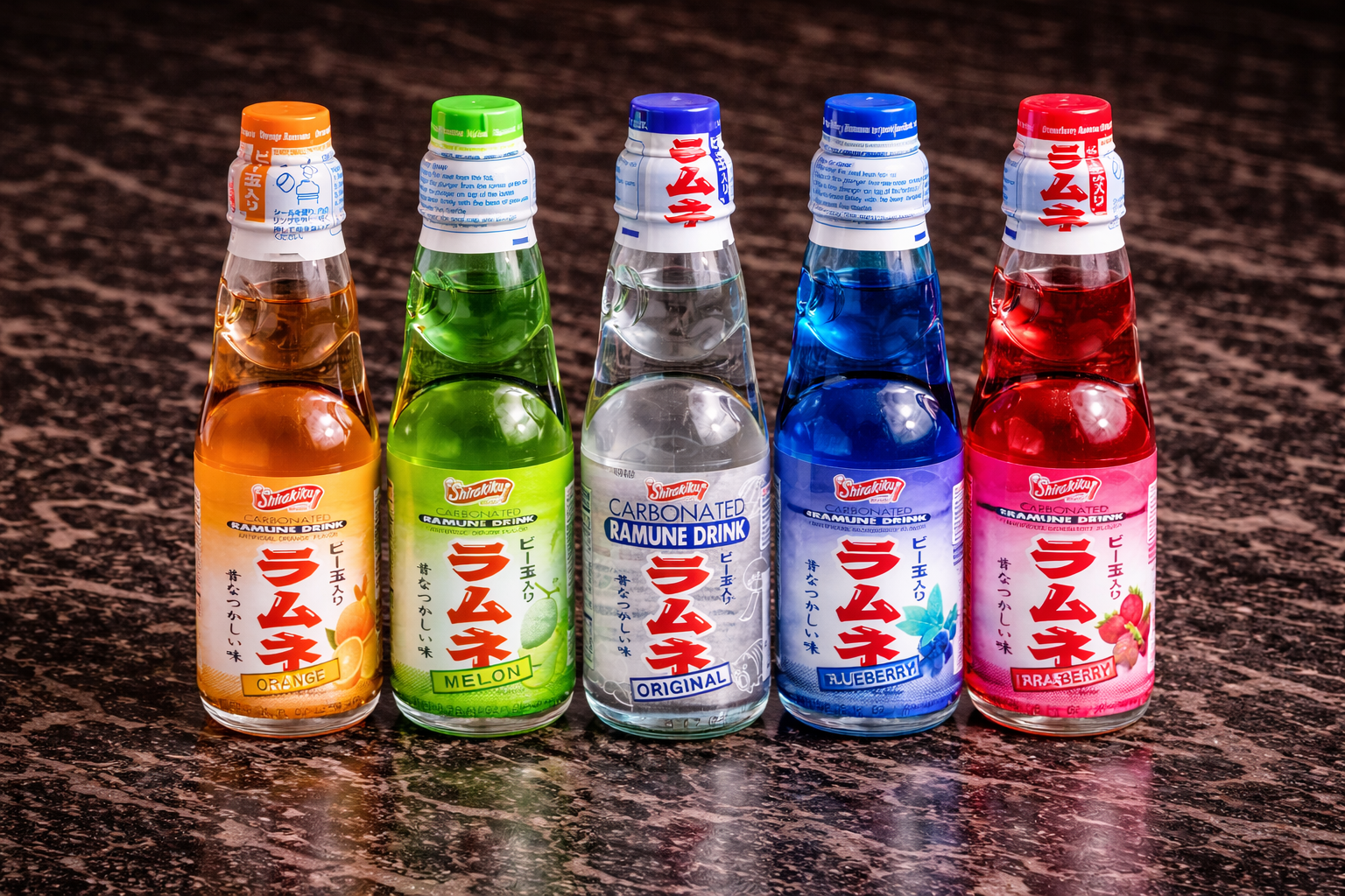 Five colorful bottles of Ramune soda with distinct labels and matching caps arranged on a dark, textured surface.