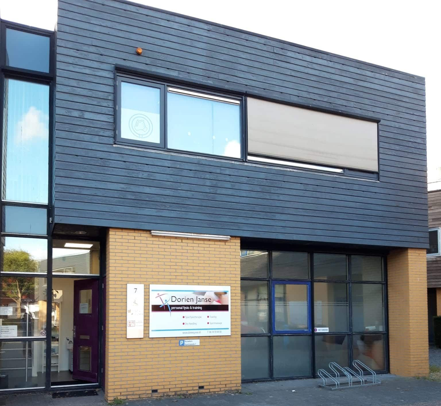 Gebouw met donkergrijze gevelbekleding, lichtbruine bakstenen en grote ramen; waarschijnlijk een kantoor.