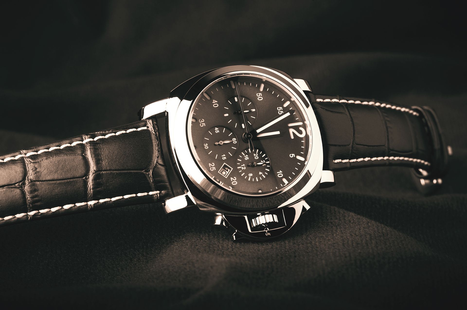 A black and white photo of a wristwatch with the number 12 on the face