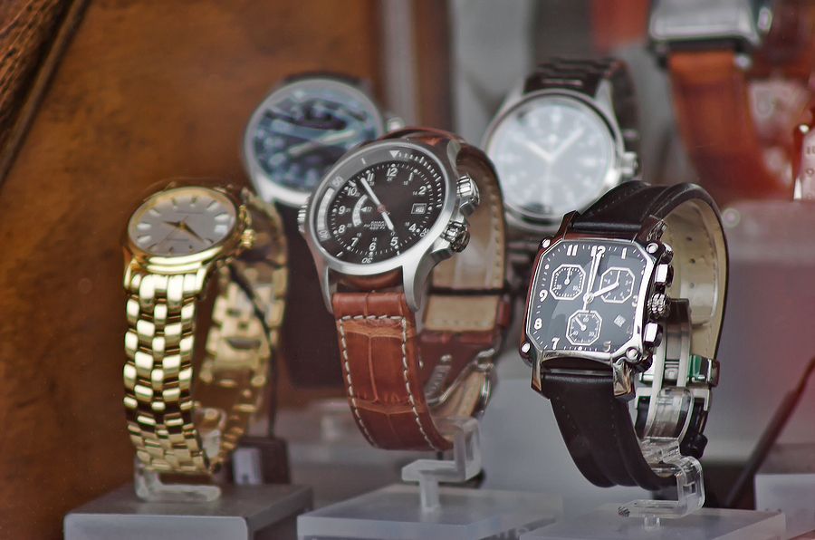 Several watches are displayed in a store window including one that says ' rolex ' on it