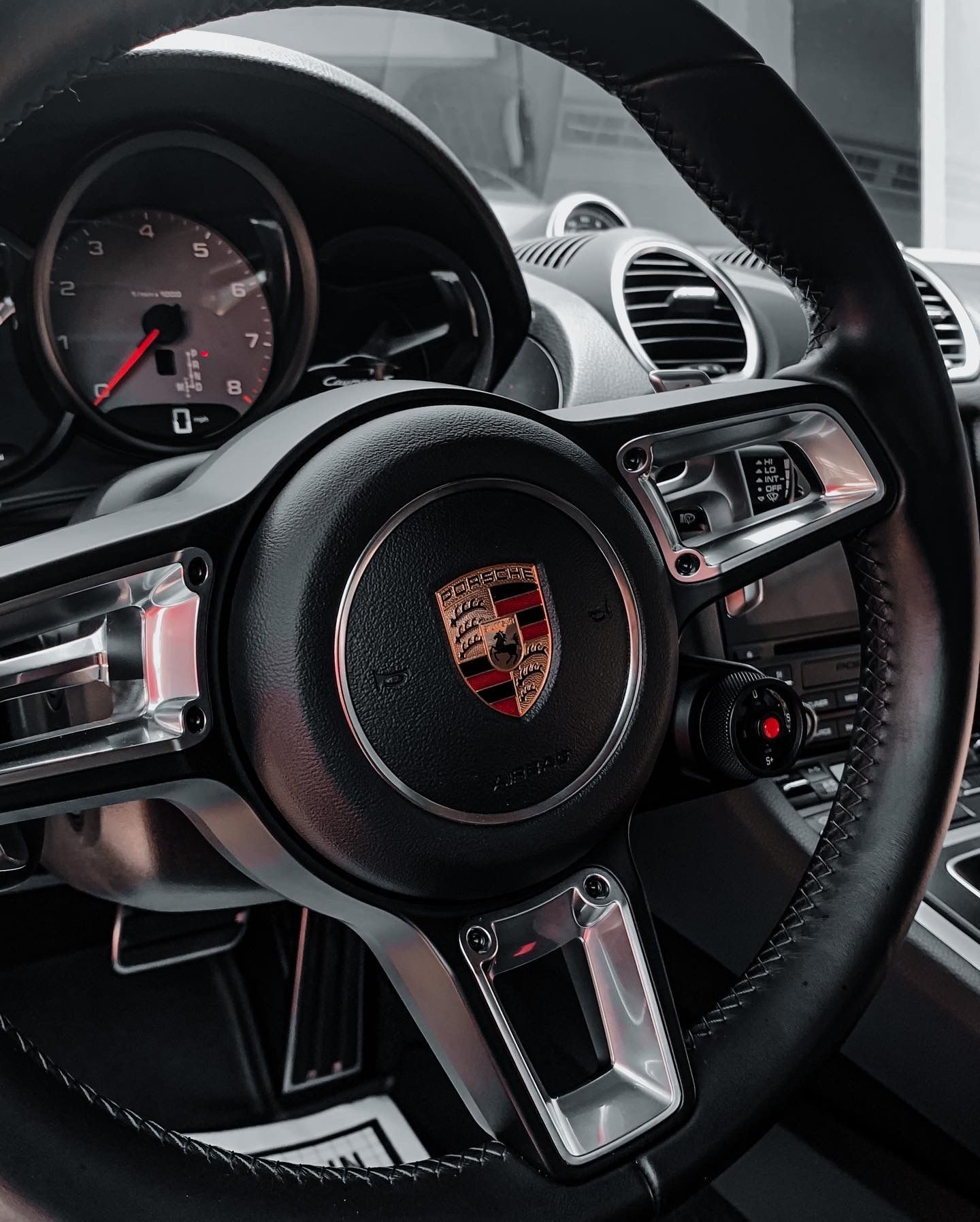 A close up of a porsche steering wheel and dashboard