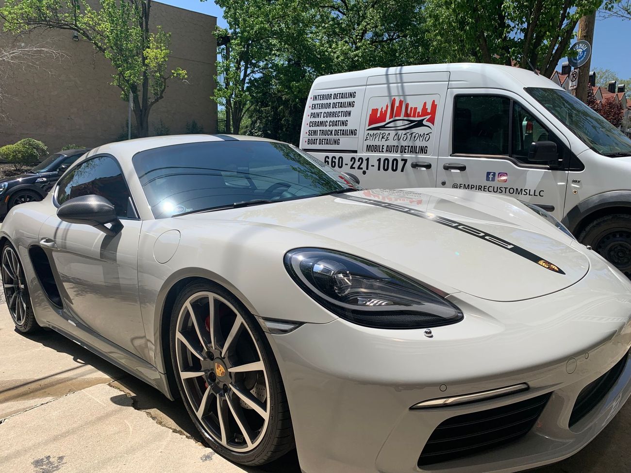 A white sports car is parked next to a white van.