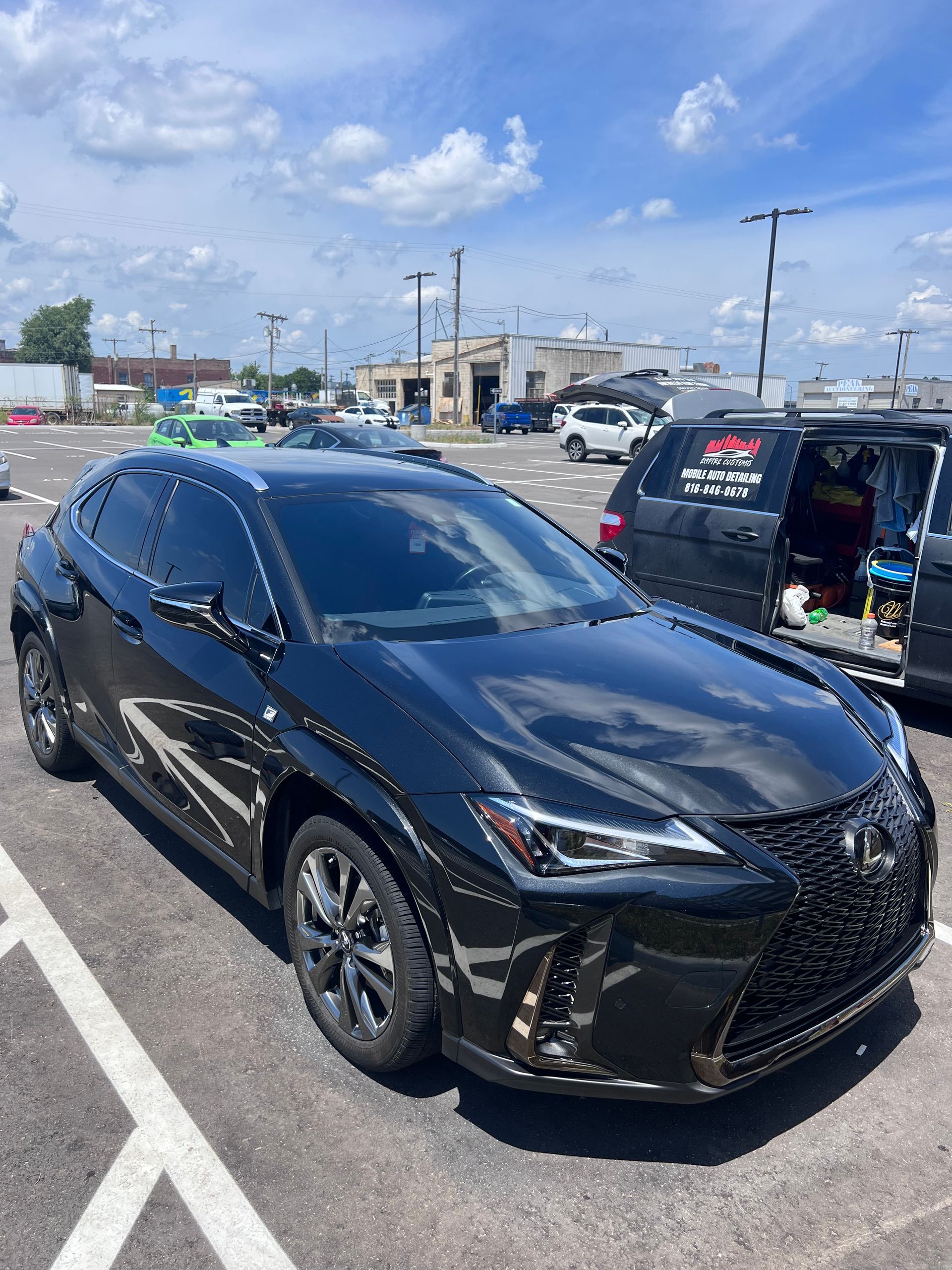 A black lexus is parked in a parking lot.