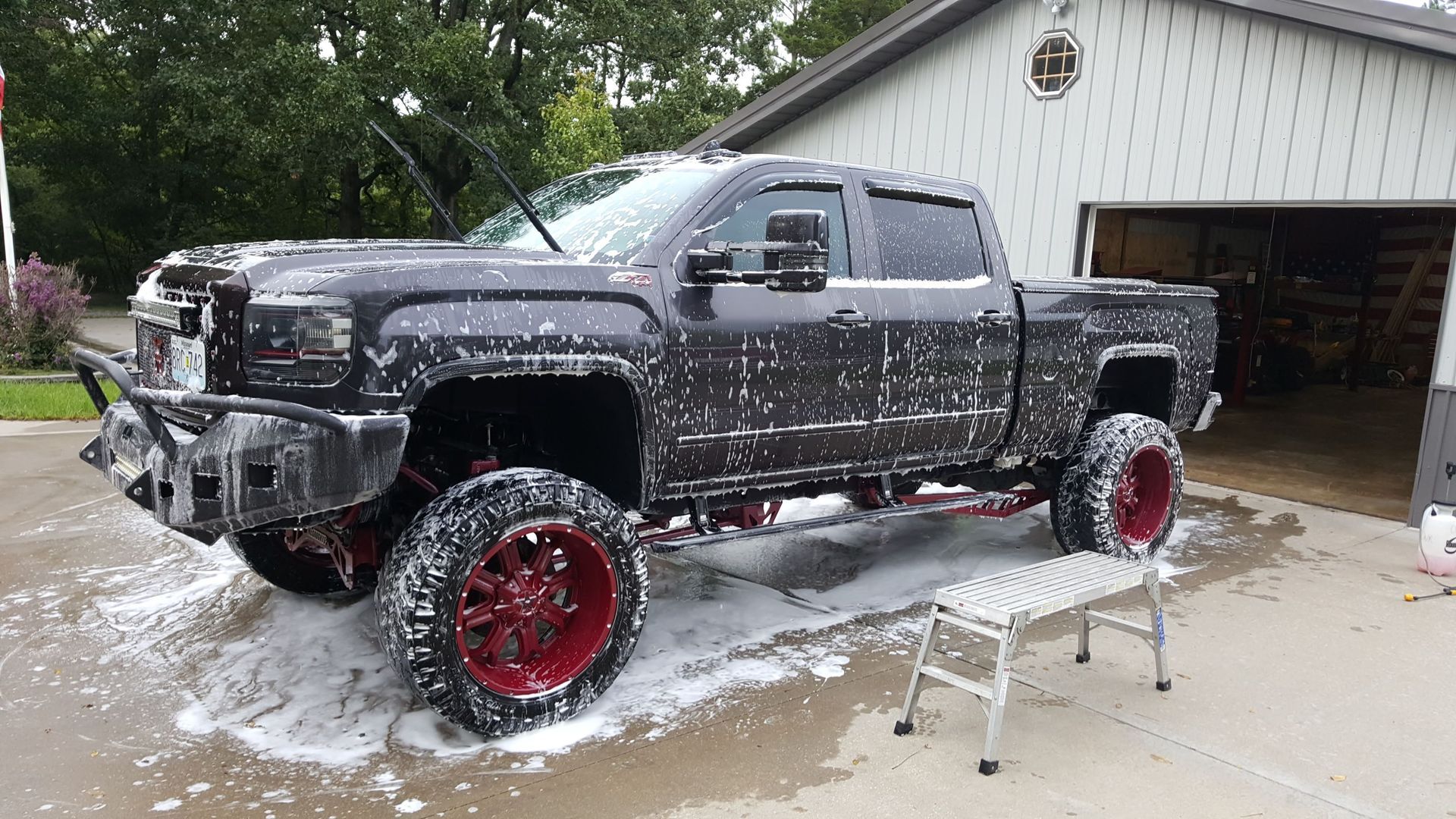 A black truck is sitting in a driveway next to a garage covered in foam.