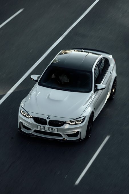A white bmw m3 is driving down a highway.
