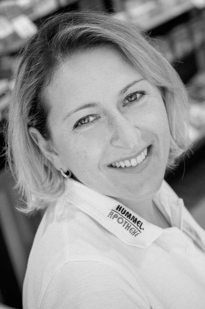 Auf einem Schwarzweißfoto lächelt eine Frau in einem weißen Hemd.