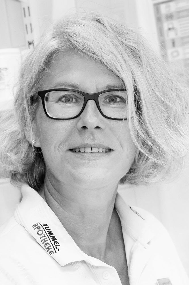 Auf einem Schwarzweißfoto lächelt eine Frau mit Brille und weißem Hemd.