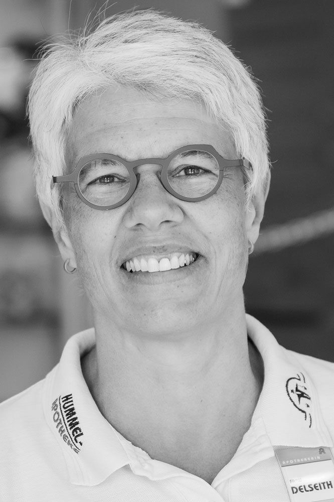 Auf einem Schwarz-Weiß-Foto lächelt eine Frau mit Brille und weißem Hemd.