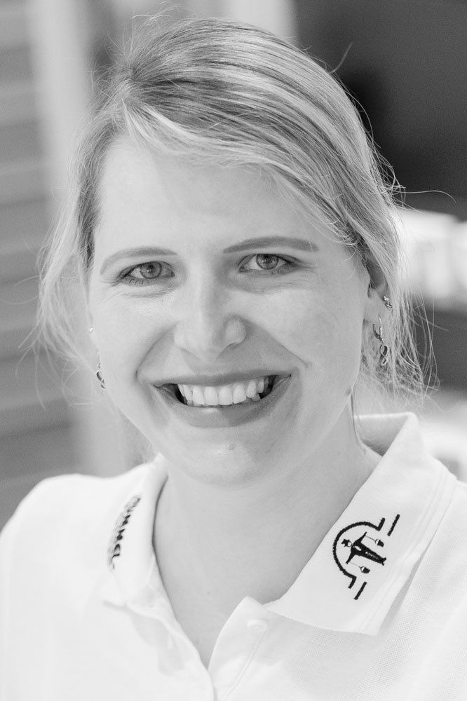 Ein Schwarzweißfoto einer lächelnden Frau in einem weißen Poloshirt.