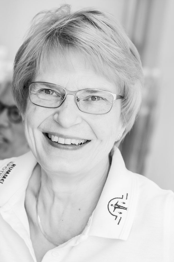 Auf einem Schwarz-Weiß-Foto lächelt eine Frau mit Brille und weißem Hemd.