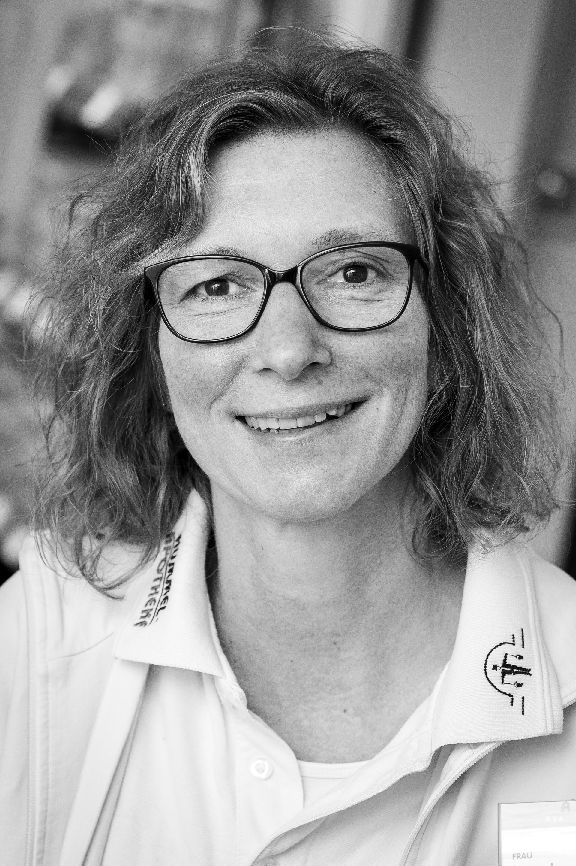 Auf einem Schwarzweißfoto lächelt eine Frau mit Brille und weißem Hemd.