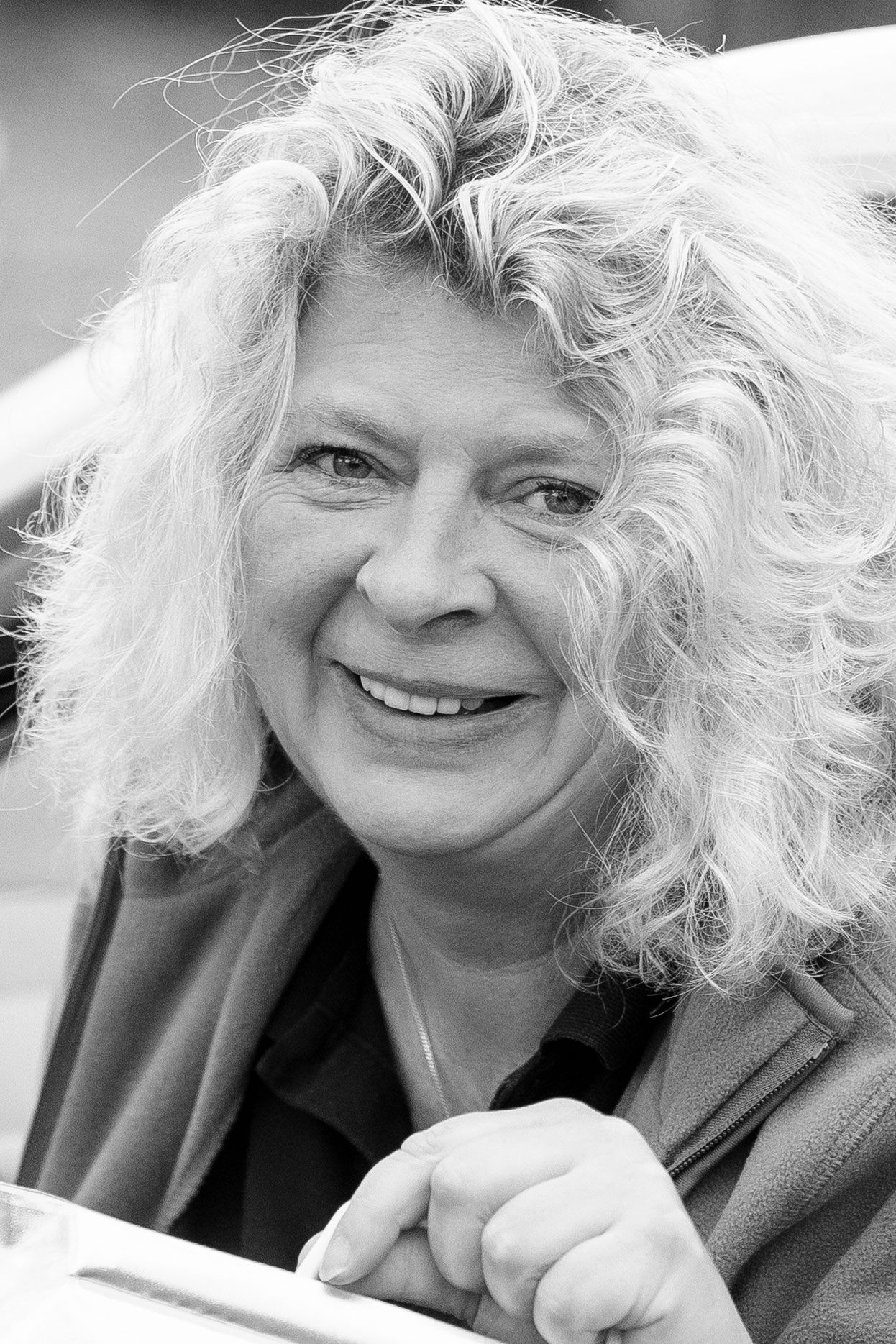 Auf einem Schwarzweißfoto lächelt eine Frau mit lockigem Haar.