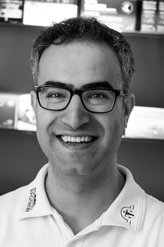 Auf einem Schwarzweißfoto lächelt ein Mann mit Brille und weißem Hemd.