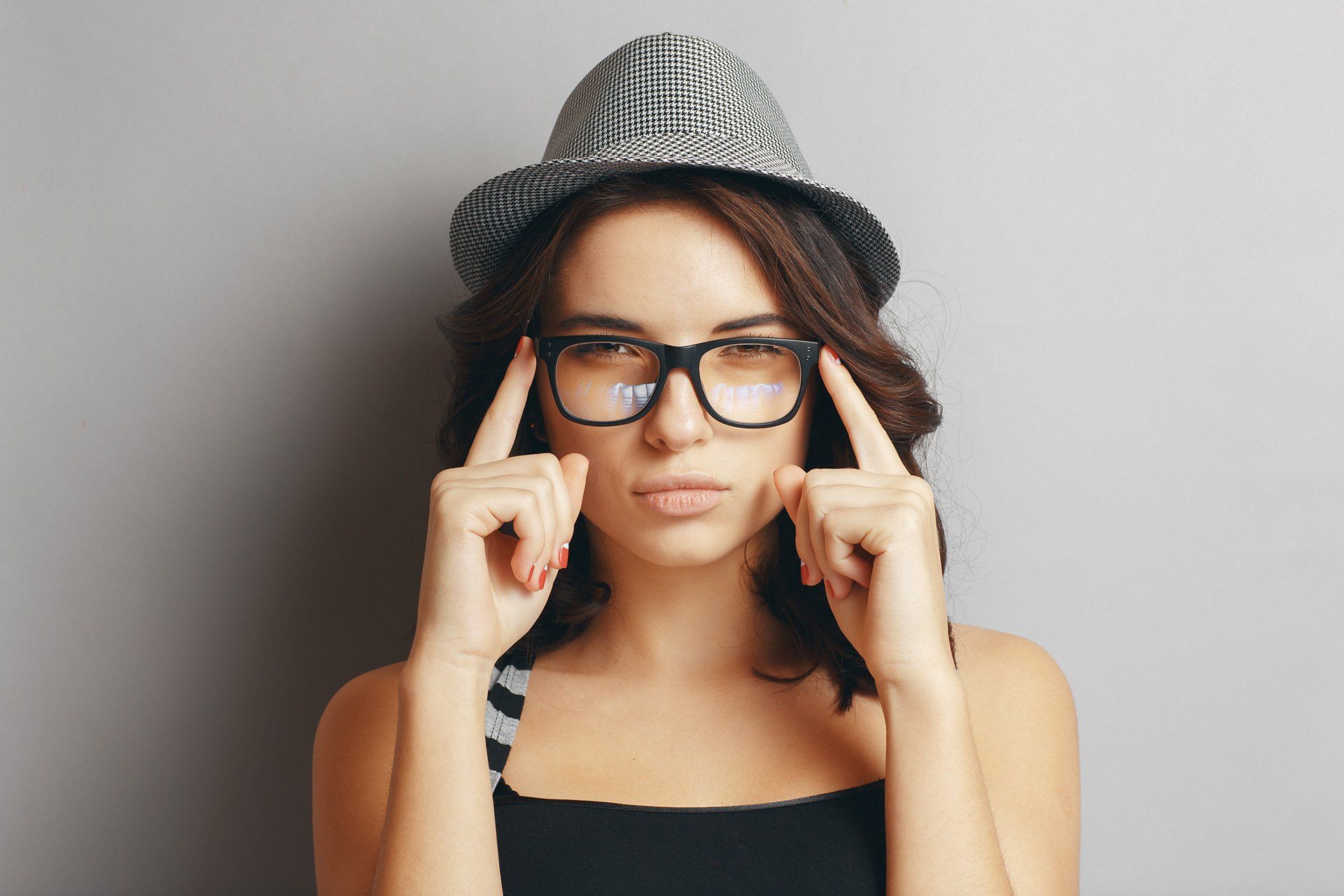 woman in hat with fingers on brim of glasses