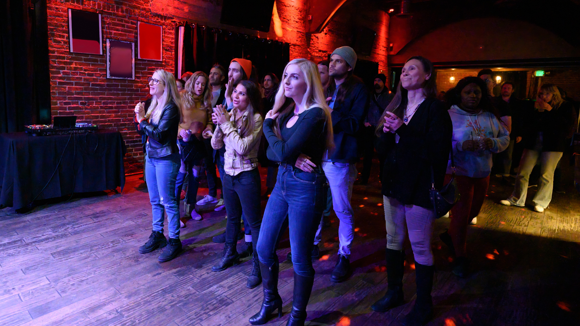 A group of people are standing in a dark room watching a performance.