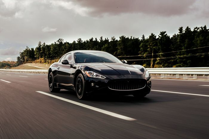 A black sports car is driving down a highway.