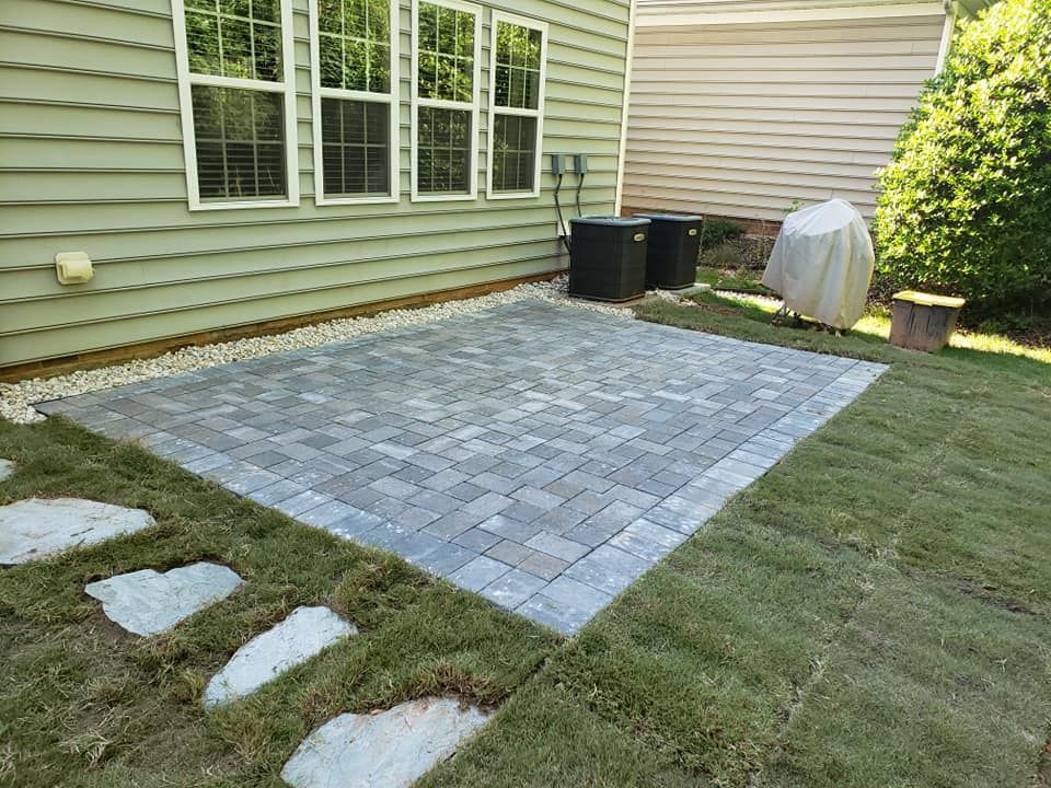 A patio with a grill in the backyard of a house.