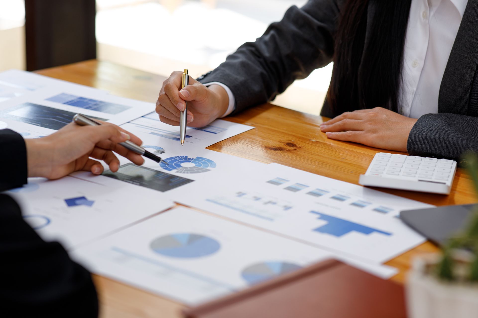 Person using a laptop, money, and calculator on a desk.