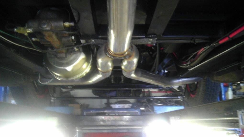 A close up of the underside of a car with a exhaust pipe.
