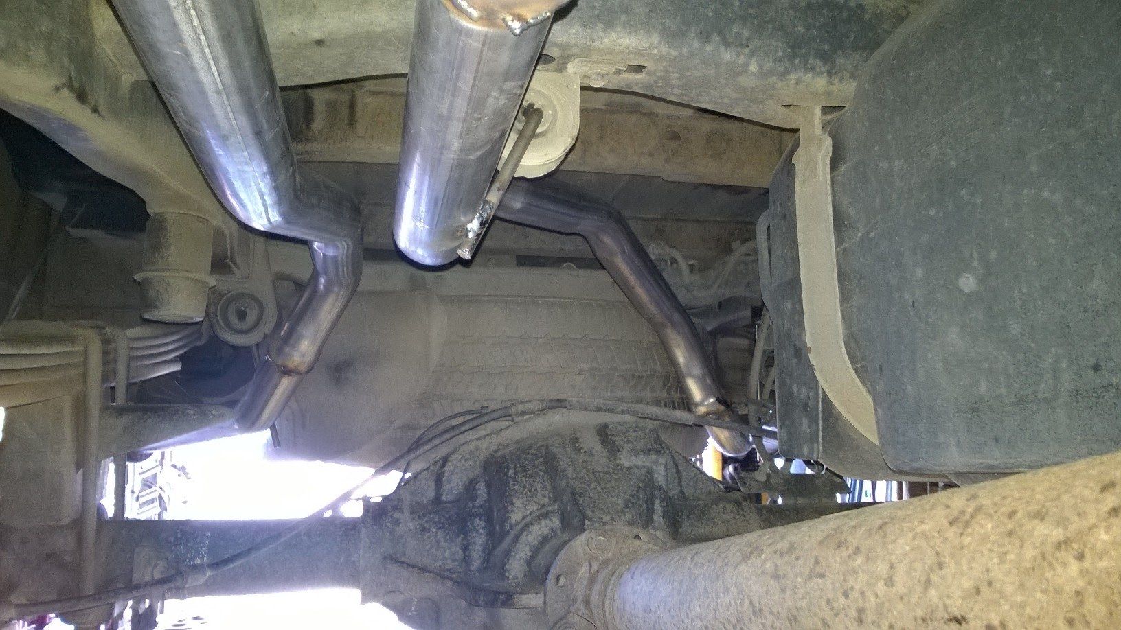 A close up of a exhaust pipe on the underside of a truck.