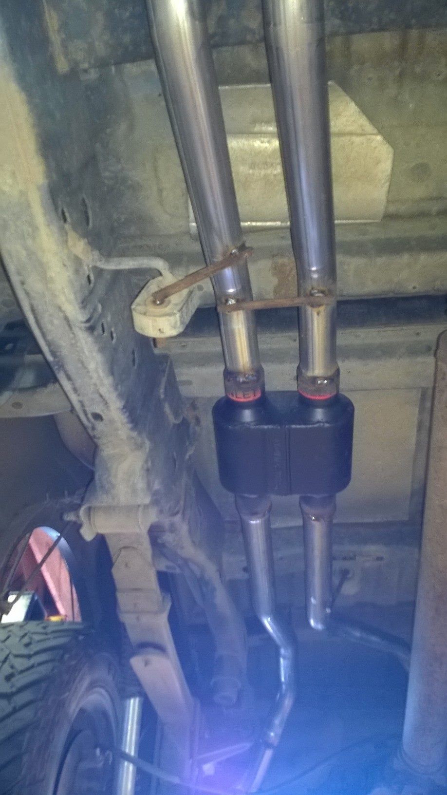 A close up of a exhaust pipe on the underside of a truck.