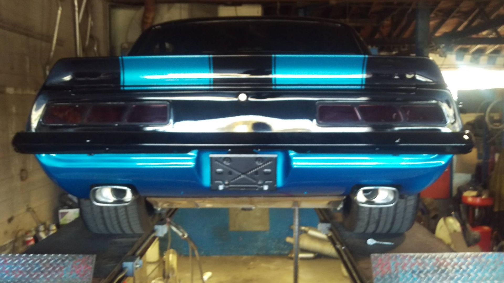 A blue and black car is on a lift in a garage