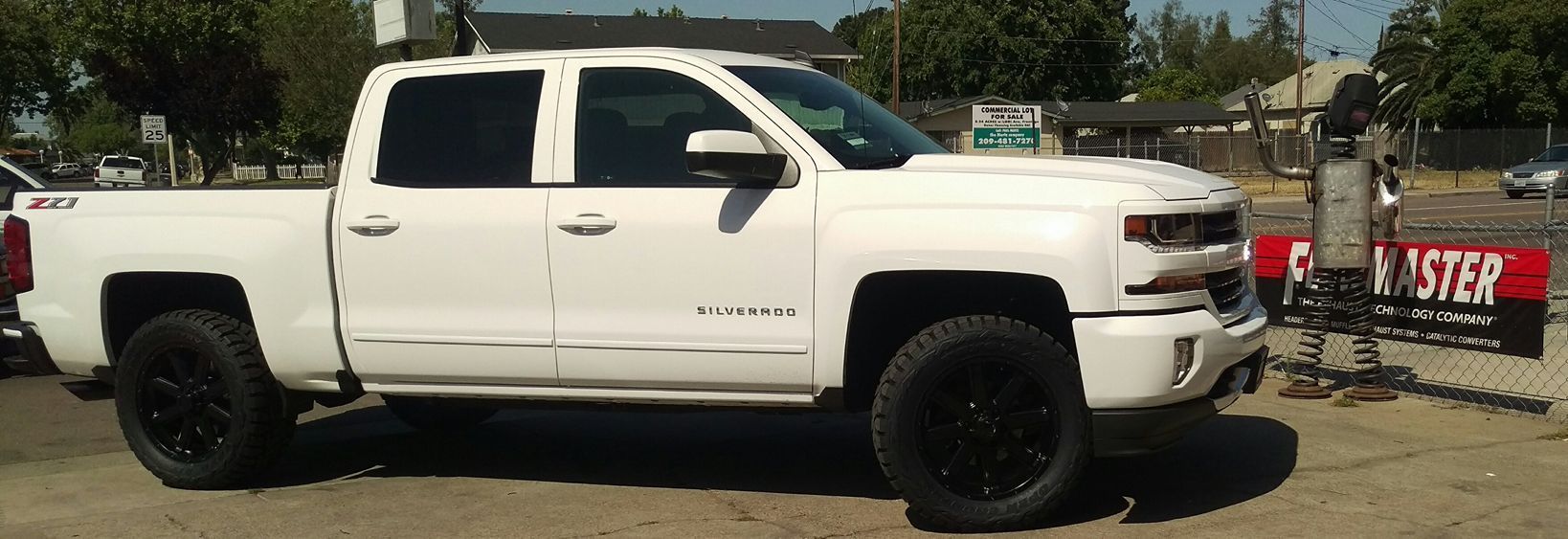 A white truck is parked next to a red sign that says register
